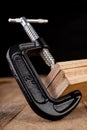 A small joinery clamp used for gluing planks. Accessories for carpenters on the workshop table Royalty Free Stock Photo