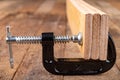 A small joinery clamp used for gluing planks. Accessories for carpenters on the workshop table Royalty Free Stock Photo