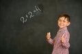 A small and joyful student solved the problem on the board and shows his thumbs up Royalty Free Stock Photo