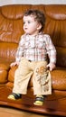 Small kid with curly hair on a leather brown sofa Royalty Free Stock Photo