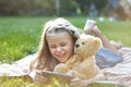 Small kid girl looking in her mobile phone together with her favorite teddy bear toy outdoors in summer park Royalty Free Stock Photo