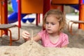 Small kid playing with sand at playground. Little girl at sandbox in park. Royalty Free Stock Photo