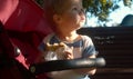 Small kid siting in a stroller and eating bun