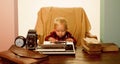 Small kid typewrite paper on retro typewriter at desk. Boy typewrite keys on vintage machine Royalty Free Stock Photo