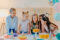 Small kids celebrate birthday party, blow candles on cake, gather at festive table, have good mood, enoy spending time together, Royalty Free Stock Photo