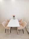 Small kitchen corner with white walls, a dining table and beige armchairs. Vase with roses as an element of interior