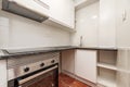 Small kitchen with recently installed white cabinets with gray worktops and stainless steel appliances and red stoneware floors