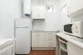 Small kitchen with white cabinets with a hot water heater, white fridge and microwave oven