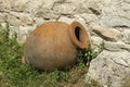 Small Kvevri or Qvevri on the grass near the stone wall. Kvevri are earthenware vessels used for the fermentation, storage and