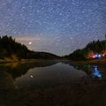 Small lake under stars at night with short rails and camping at summer Royalty Free Stock Photo