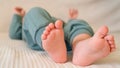 The small legs of a newborn lie on the bed. Baby in green clothes. Focus on legs, white background. Royalty Free Stock Photo