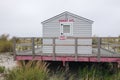 Small lifeguard shack with a large porch on a beach withe a beach closed sign