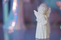 Small light white yellow marble figurine of an angel in dress on a pearlescent pink blue blurred bokeh Royalty Free Stock Photo