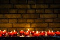 Small lighted candles in red glass candlesticks in front of a brick wall Royalty Free Stock Photo