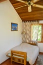 Small lightful bedroom with curtains on windows and rug on the floor.