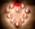 A small lighting lamps with red color aromatic paraffin in a small glasses arrange in heart form with a red rose symbol of love
