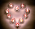 A small lighting lamps with red color aromatic paraffin in a small glasses arrange in heart form on a white floor in the night