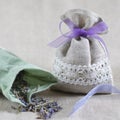 Small linen sack filled with dried lavender decorated with lacework and violet ribbon coqueand and one sachet is opened. Top view