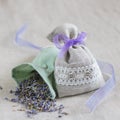 Small linen sack filled with dried lavender decorated with lacework and violet ribbon coque, two sachets, one is opened