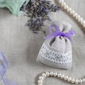 Small linen sack filled with dried lavender decorated with lacework and violet ribbon, two sachets, one is opened and