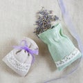 Small linen sack filled with dried lavender decorated with lacework and violet ribbon coque, two sachets, one is opened. Top view