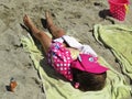 Small Little Girl Lying and Sleeping on Towel on Sand Beach Covered by Pink Towel and with Hat on her Head Royalty Free Stock Photo