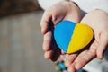 Small little kid hold heart shaped stone with Ukraine national flag or anthem