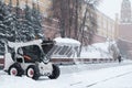 A small loader excavator bobcat removes snow from the sidewalk near the Kremlin walls during a heavy snowfall