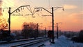 Small locomotive moving away from camera in winter at sunset
