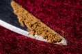 Small loose cinnamon on the tip of a knife on a red wool background macro Royalty Free Stock Photo