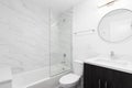 A bathroom with a dark wood cabinet, circular mirror, and marble shower. Royalty Free Stock Photo