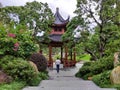 Small man figure go to Chinese pavilion among the trees in Asian style park, afar view Royalty Free Stock Photo