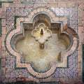 Small marble fountain surrounded by bricks and tile in the gardens of the Real Alcazar in Seville, Spain. Royalty Free Stock Photo