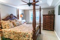 Small Master bedroom with a large four poster wood bed and an old fashioned floral comforter with a window. Royalty Free Stock Photo