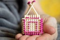 A small match house in the hands of an old woman, a homemade house made of matches in her hands