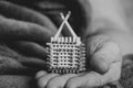 A small match house in the hands of an old woman, a homemade house made of matches in her hands