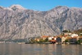 Small Mediterranean village with stone houses with red roofs against gray mountains. Montenegro, Bay of Kotor