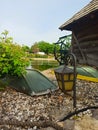 a small metal outdoor lamp on the river bank, next to an old mill