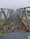 A small metal pier on the banks of the river Danube in Passau city, Bavaria, Germany. Autumn leaves on metal pier and fog. Royalty Free Stock Photo