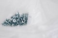 Small metal screws in plastic bag on white wooden background. Construction equipment concept. Top view. Copy, empty space for text Royalty Free Stock Photo