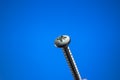 Small metal threaded screw. Close up studio macro shot, isolated on blue background Royalty Free Stock Photo
