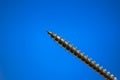 Small metal threaded screw. Close up studio macro shot, isolated on blue background Royalty Free Stock Photo