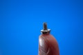 Small metal threaded screw held by Caucasian male hand between fingers. Close up studio macro shot, isolated on blue background Royalty Free Stock Photo