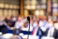 Small microphone behind the podium for the MC, master of ceremony, with a blurry crowd audience in the background in a seminar