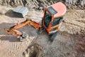 A small mini excavator is working on a construction site. Close-up. View from above. Work in cramped conditions. Excavation Royalty Free Stock Photo