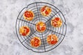 Small pizzas topped with cheese, tomato, yellow and red bell peppers and salami sausage on round black grid, top view Royalty Free Stock Photo