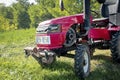 Small mini red modern new tractor standing at farm, field, nature countryside during sunny summer day close up. Small