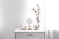 Small mirror and different makeup products on chest of drawers