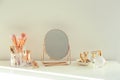 Small mirror and makeup products on white dressing table