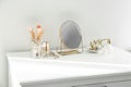 Small mirror and makeup products on dressing table indoors